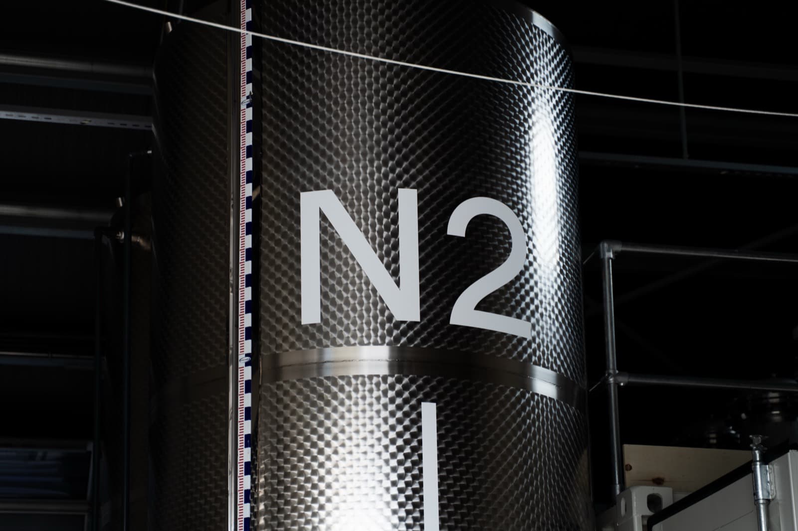 The N2 mark on the dimpled stainless flank of a product tank, lit against a dark hall